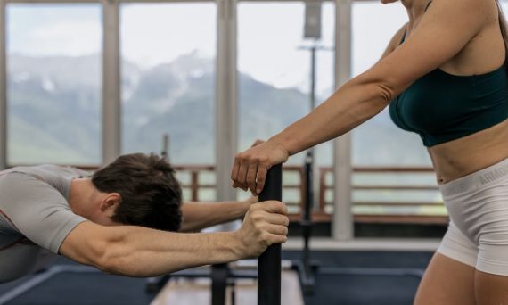 A couple working out together at an indoor gym with mountain views.
